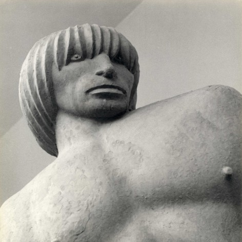 Black and white photo of an imposing figure, sculpted in clay, photographed from a dramatic angle.