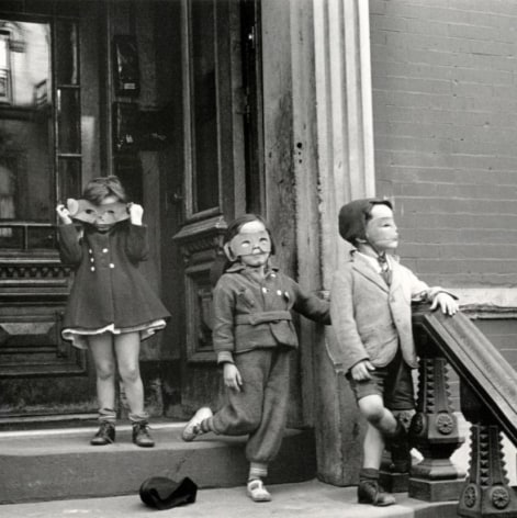 Black and white photo of three kids walking out the door of a brownstone wearing homemade masks.