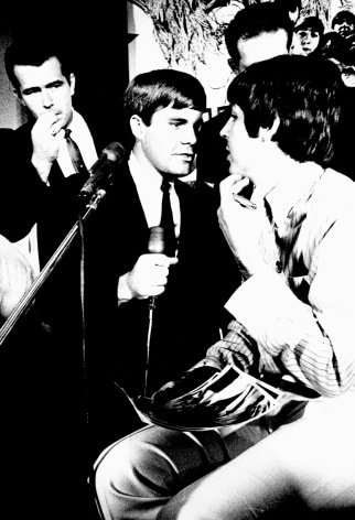 Black and white image from a Beatles press conference in 1966. Paul McCarteny speaks to journalists.
