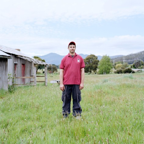 Employee of an apple museum standing in a field with red hat and shirt