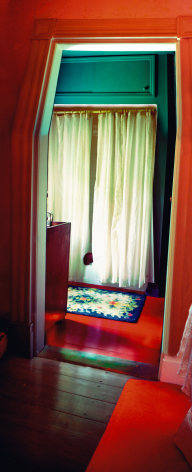 Vertical panoramic photo of a brightly colored domestic interior, light comes through a drawn curtain.