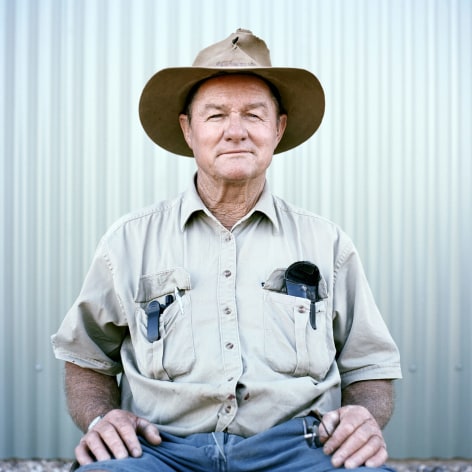 Color photo of a dinosaur museum employee in a sun hat with pocket protector.