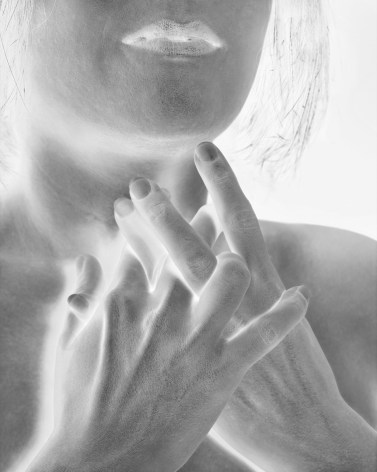 Black and white photographic closeup image of woman holding her interlaced fingers to her throat.