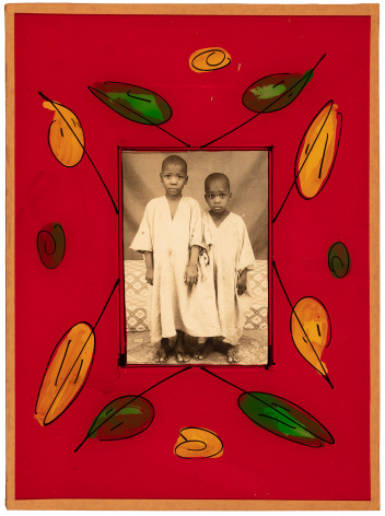 Black and white photo portrait of two young Black children, framed in a red glass frame with hand painted leaves.