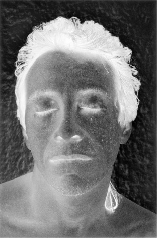 Black and white negative photographic image of a man's face with his eye closed.