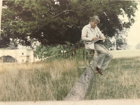 man sitting on a fence drawing