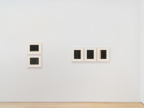 installation view of multiple works on paper in a white room