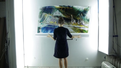 image of a woman holding a scrolled up photograph on the wall