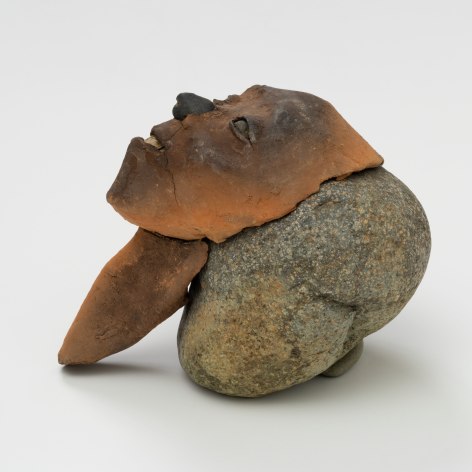 a ceramic head on top of a rock