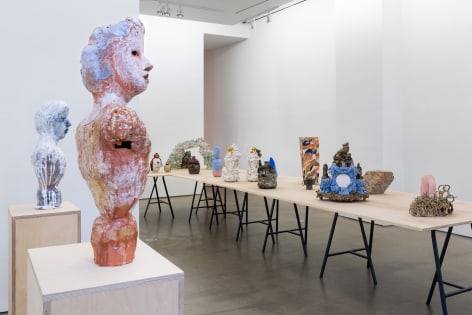An installation view of the group exhibition &quot;Morph&quot;. There are many sculptures on a table in the gallery. Busts are on pedestals