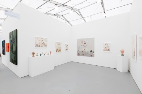 Installation image of the art fair booth at UNTITLED Miami. Framed works are on the walls and ceramic sculptures are on podiums
