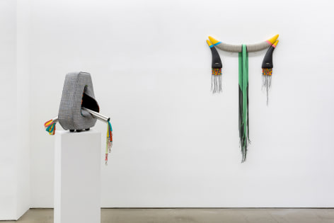 Installation view of Trish Tillman's exhibition &quot;Stage Diver&quot;, which shows plush sculptures on the walls and on a floor pedestal.