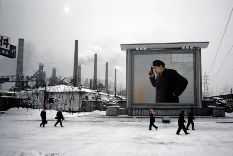 Hiroji Kubota, At the Kim Chaek Ironworks; the billboard shows Kim Il-sung peering into a furnace, Chongjin, North Korea, 1986, dye-transfer print, 20 x 24 inches/50.8 x 61 cm &copy; Hiroji Kubota/Magnum Photos