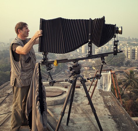 Robert Polidori standing on a rooftop in Mumbai shooting the city below, using an enormous