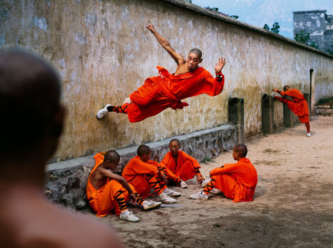 A young monk runs along the wall over his peers at the Shaolin Monastery in Henan Province, China, 2004,&nbsp;ultrachrome print, 40 x 60 inches/101.6 x 152.4 cm