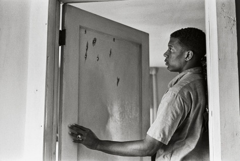 Jerome Smith Inspects Bullet Holes in Door, 1963, Silver Gelatin Photograph