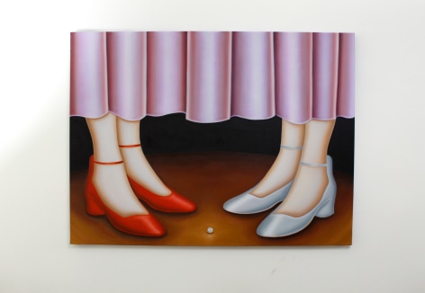 Two sets of high heeled women's feet stand facing each other on a theater stage under a velvet pink curtain. One small white pearl is between them.
