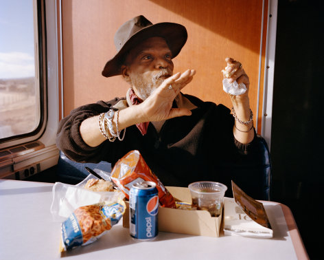 Person with snacks on a train, by McNair Evans