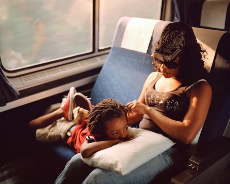 Adult and child in train seats, by McNair Evans