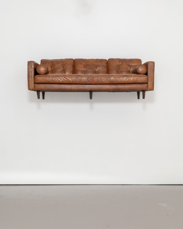 Brown leather coach mounted to wall, by Randy Shull