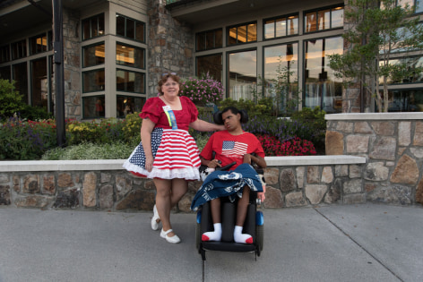 Stacy Kranitz  Gatlinburg, Tennessee, 2016  Archival Pigment Print  16 x 24 inches, Edition of 7  27 x 40 inches, Edition of 3, Woman in American Flag dress with man in a wheelchair, Tennessee