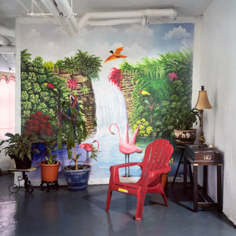 Untitled #51 (tropics), 2013  from the series Basement Sanctuaries  Archival pigment print  16 x 16 inches  Edition of 5, interior of a basement in NYC with a tropical wall mural of a waterfall, a red plastic chair and potted plants