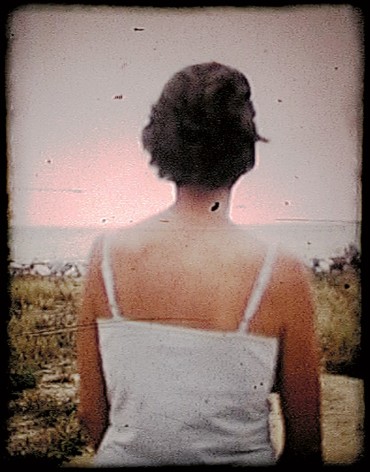 Colby Caldwell  fig (2), [still from The Last Photograph], 2004  Archival pigment print mounted on wood panel with a hand waxed surface  15h x 12w in, color photograph of a woman from behind wearing a white camisole, landscape in the background.