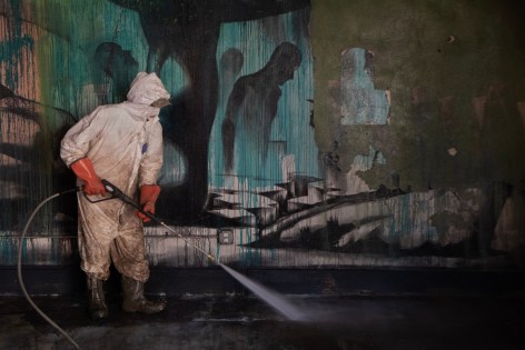 a figure in a tyvek suit pressure washes the interior of a building impacted by floodwaters in Marshall, North Carolina