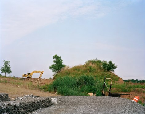 Old Landscape with New Interior Road and Gabion Wall, West Mound, 2019, Photograph of a mound of old landscaping, along a new road with big digger and other construction machinery in the distance, West Mound, Freshkills, NYC