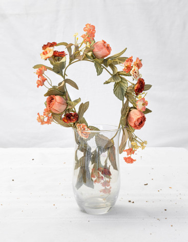 Photograph of a vase with a ring of peach roses and other flora