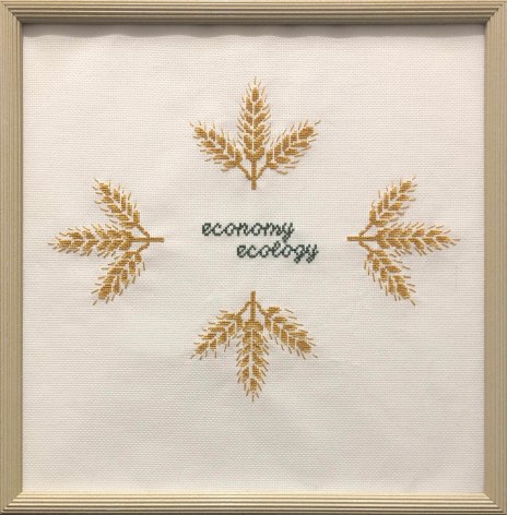 Kirsten Stolle  Economy over Ecology, 2014  Embroidery floss on aida cloth in a vintage frame  14h x 16w in -The words economy and ecology are embroidered in the center of the aida cloth