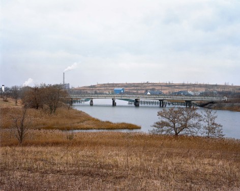 Jade Doskow  Landscape, Freshkills (After Bruegel), 2018  Archival pigment print  40h x 50w in 101.60h x 127w cm, industrial landscape in winter reminiscent to works by Peter Bruegel the elder, rust colored grass in the foreground punctuated by a winding river, multiple bridges and smoke stacks in the backgroung
