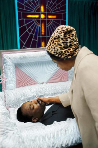 Image of MLK in casket with woman leaning over. By Burk Uzzle.