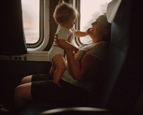 Person with baby on train, by McNair Evans