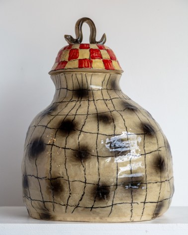 gourd shaped hand coiled vessel with lid. Underglaze has black dots and black crosshatching, the lid is red with a blue handle