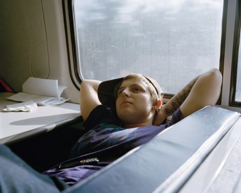 Person reclining on train bench, by McNair Evans