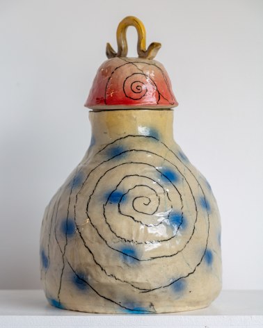 gourd shaped hand coiled vessel with lid. Underglaze has blue dots, black spirals. the lid is red with a yellow handle