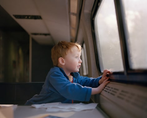 Child looking out train window, by McNair Evans