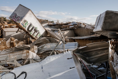 A pile of debris including tractor trailers is piled up on a flooded roadway