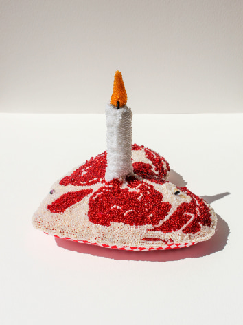 hand embroidered soft sculpture of a heart shaped piece of red meat with a candle in the middle