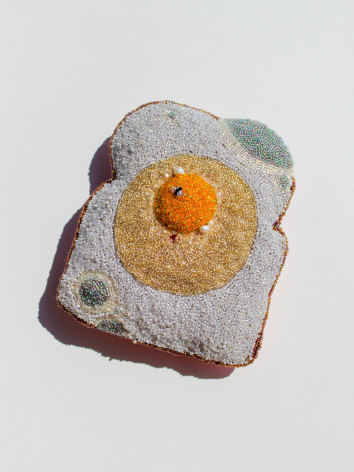 hand beaded soft sculpture  of a moldy piece of bread with a sunny side up egg on top and a single black fly