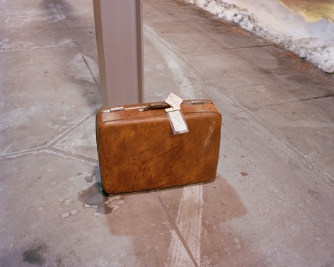 Brown suitcase on train platform, by McNair Evans
