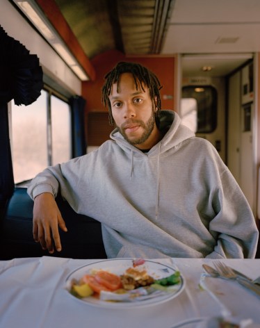 Person at table with food on train car, by McNair Evans