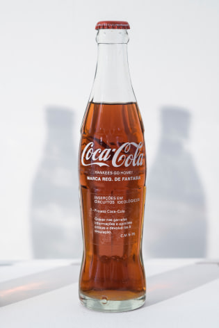 Cildo Meireles,&nbsp;Insertions into Ideological Circuits: Coca Cola Project, detail, 1970-2018. 3 glass bottles, 3 metal caps, liquid, and adhesive labels with text, 53 1/2 x 22 x 14 in (135.9 x 55.9 x 35.6 cm.)&nbsp;
