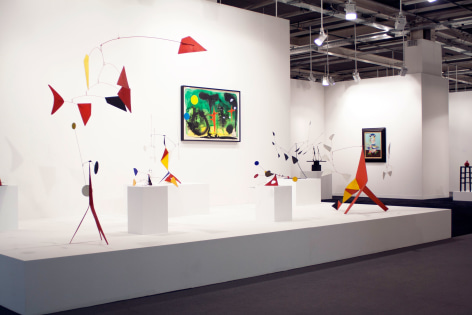 Installation view of Art Basel | Basel 2014, booth A8 featuring a mobile by Alexander Calder called, &quot;Un Noir et un Jaune&quot; (One black and one yellow), made in 1972, the materials are metal and wire hanging mobile 91.4 x 218.4 x 50.8 centimeters. (36 x 86 in. x 20 inches.). There is also five small standing mobile in the background and two paintings. &copy; 2018 Calder Foundation, New York / Artist Right Society (ARS), New York. &copy;Helly Nahmad Gallery NY