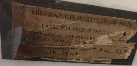 Image of the label verso fragment on &quot;The Silk Hat&quot; painting by Arna Brittin.