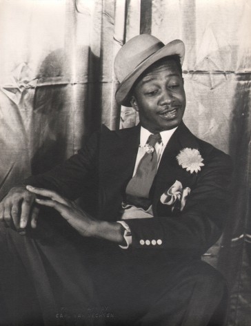 Carl Van Vechten, Avon Long as Sporting Life, Porgy &amp; Bess, ​1942. Subject in a seated pose with legs crossed and hands on knee, looking down and to the right.