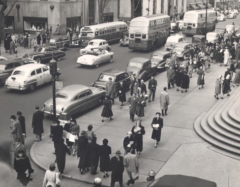 08. Simpson Kalisher, Untitled, ​c. 1949. Many pedestrians walking on a street corner from a slightly elevated view. Cars and double-decker busses can be seen on the street.