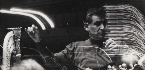 06. David Attie, Leonard Bernstein, rehearsal at Carnegie Hall, ​1959. Multiple-exposure photograph featuring a man with arms raised as if conducting and streaks of light.