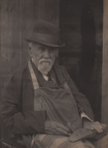 Doris Ulmann, Untitled (Cobbler), ​1928&ndash;1934. Seated man in a hat and apron with hands in his lap holding a shoe.